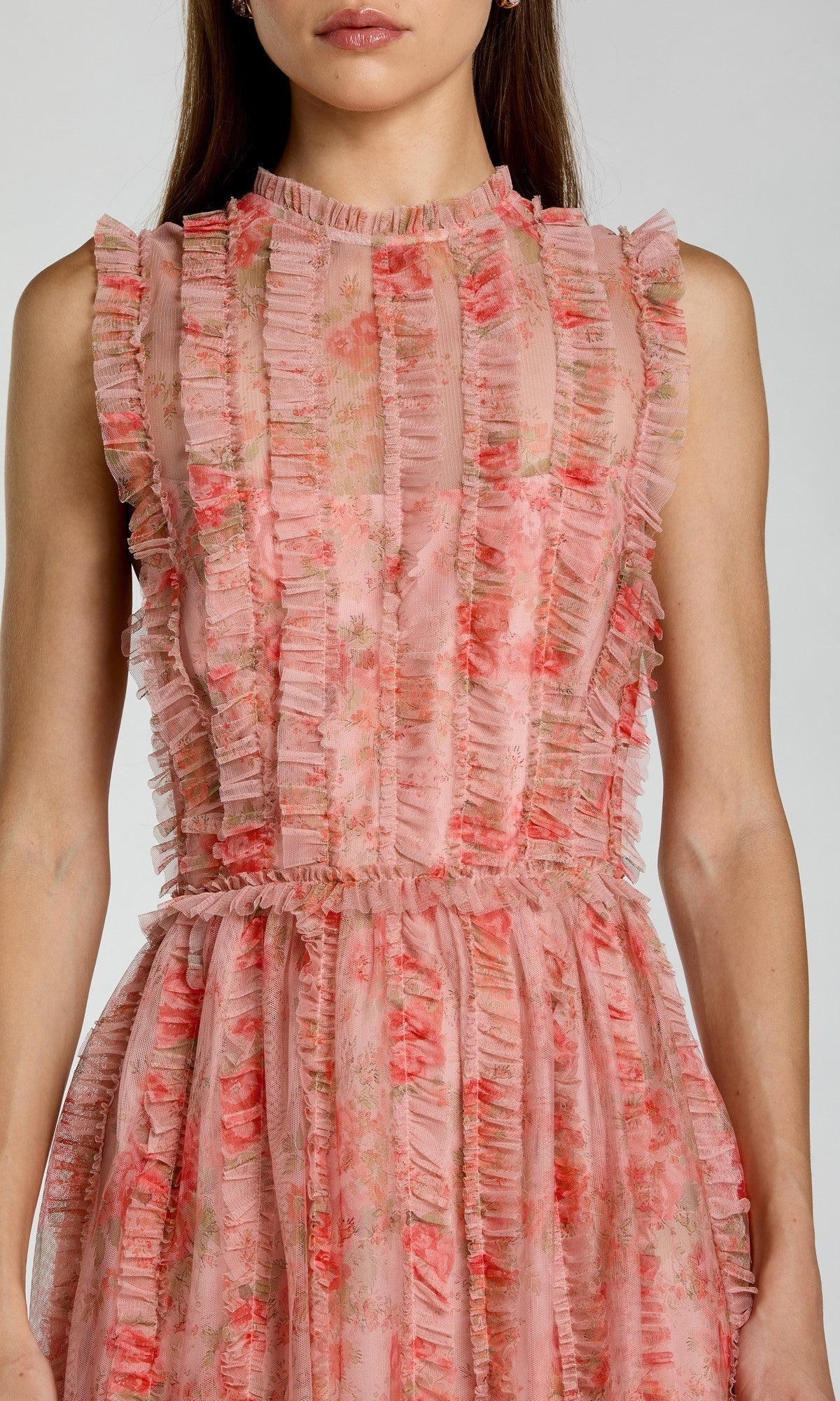 Wearing the Long Formal Dress: Mac Duggal 8309, a woman stands against a neutral background. This sleeveless pink floral midi dress features elegant vertical ruffle details.